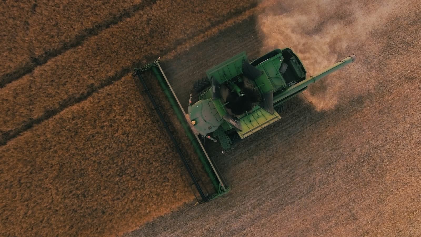 Aerial view of a John Deere combine harvesting a grain field.