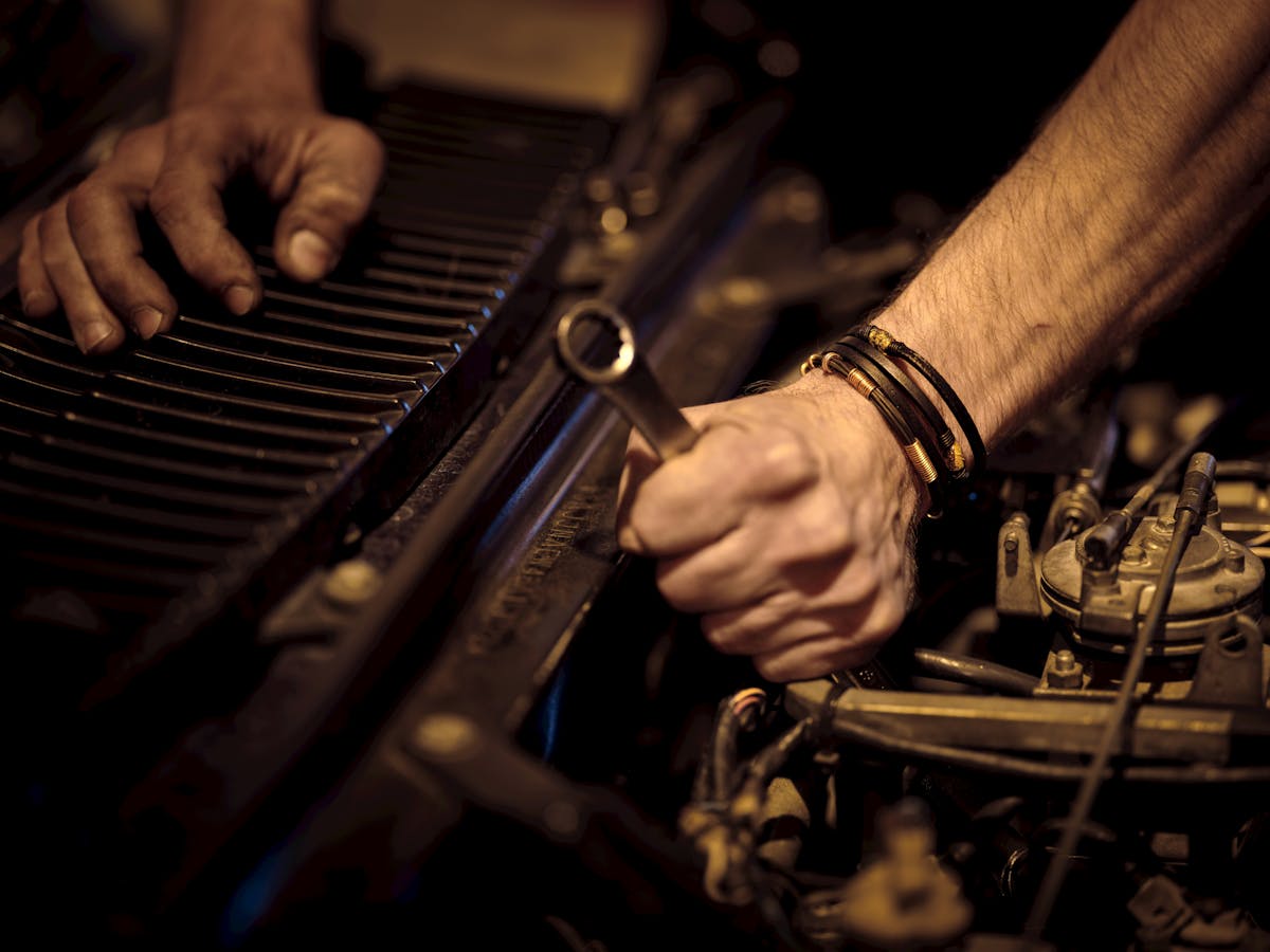 Mechanic's hands turning a wrench deep in an engine bay.