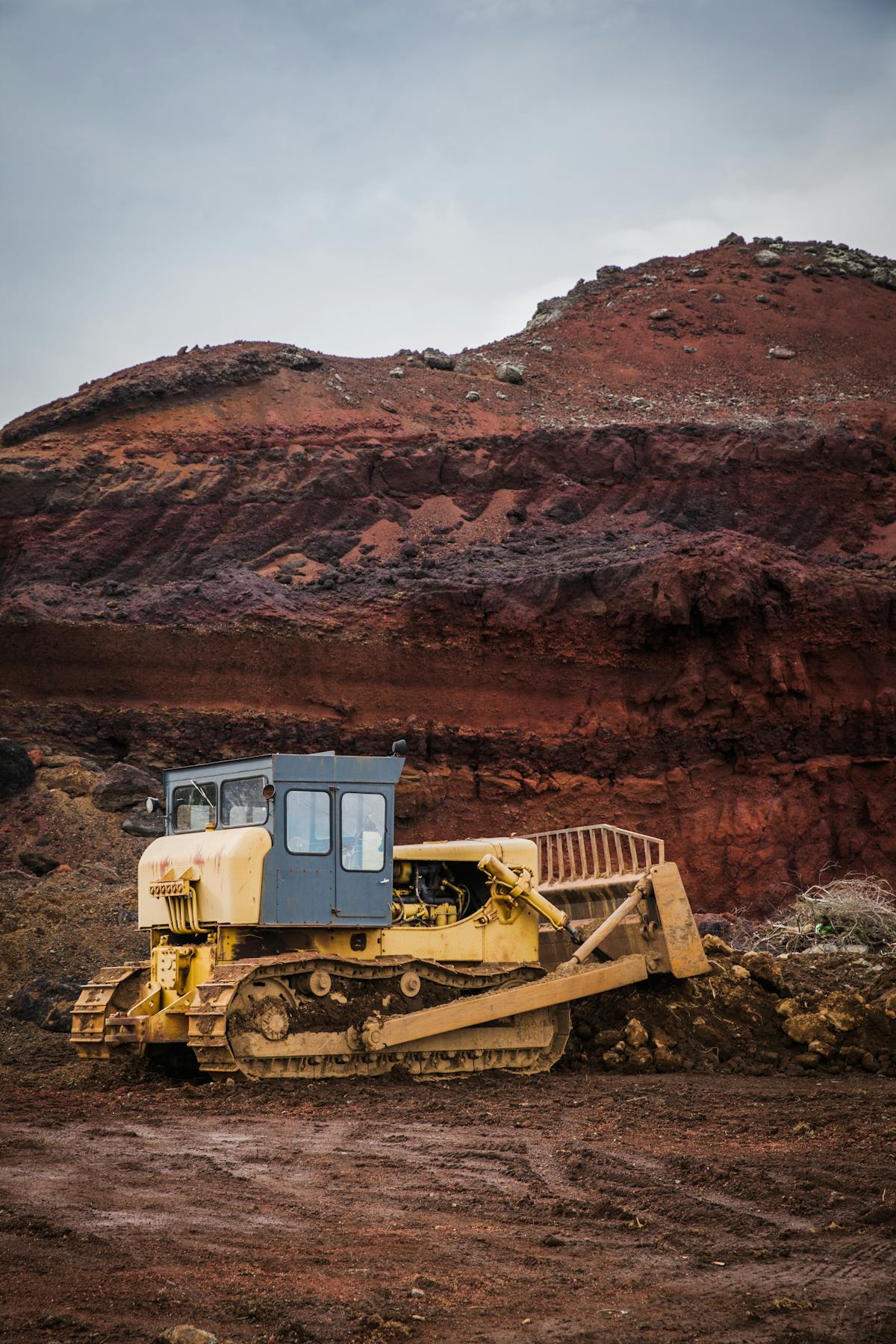 Crawler dozer working below a red rock embankment.