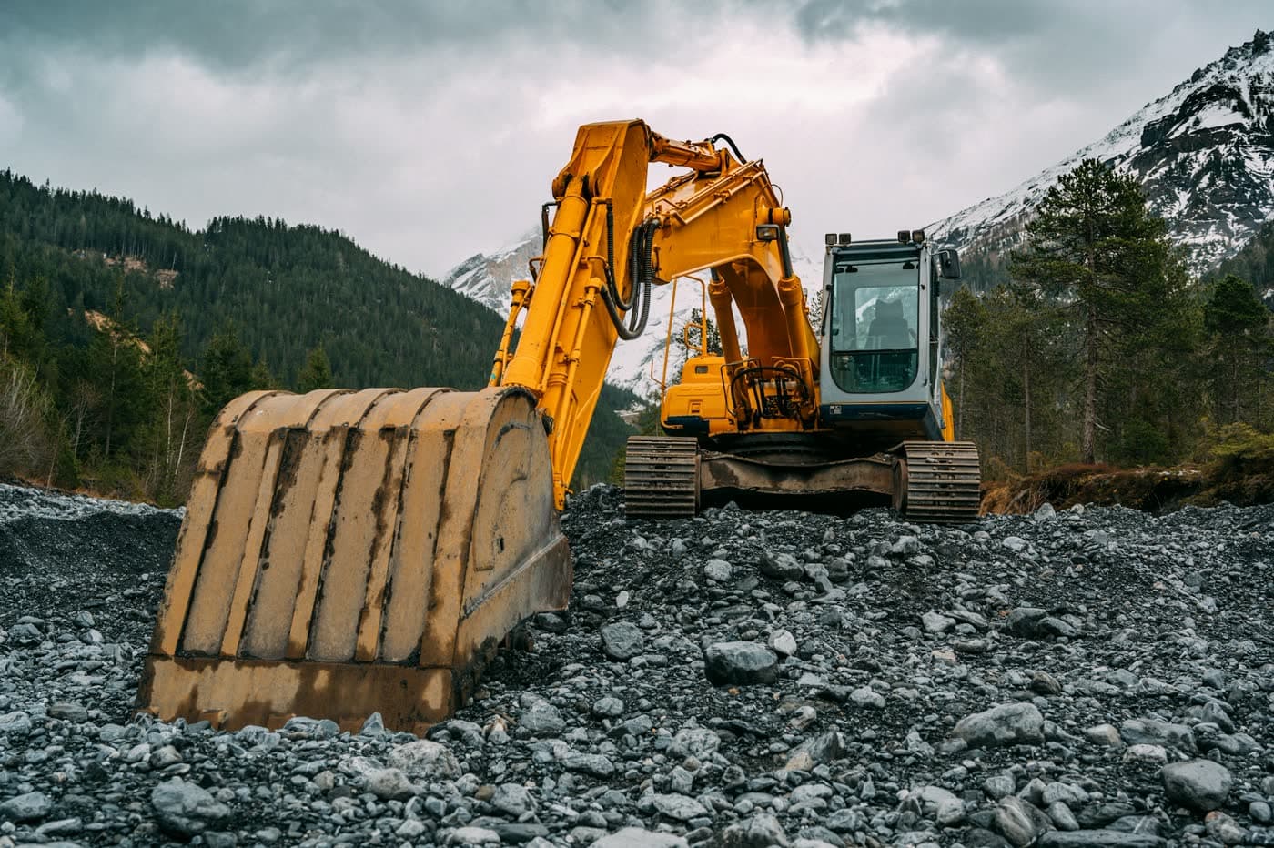 Tracked excavator parked on rocky ground with the bucket down for inspection.