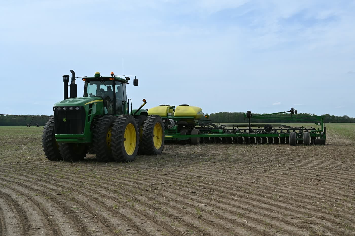 John Deere tractor pulling an air seeder — the kind of used farm equipment JSD inspects before purchase.