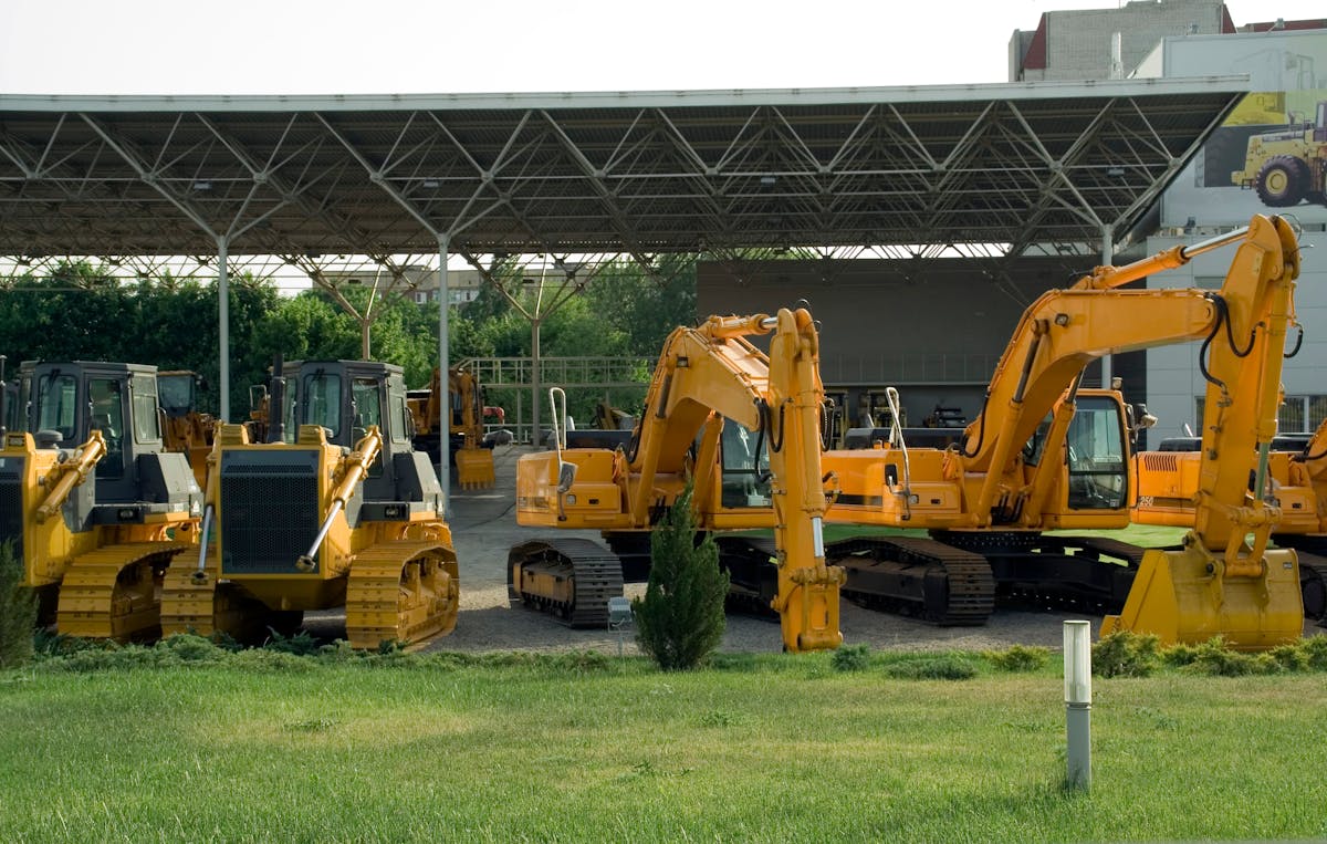 Crawler dozers and excavators lined up in an equipment yard for inspection.
