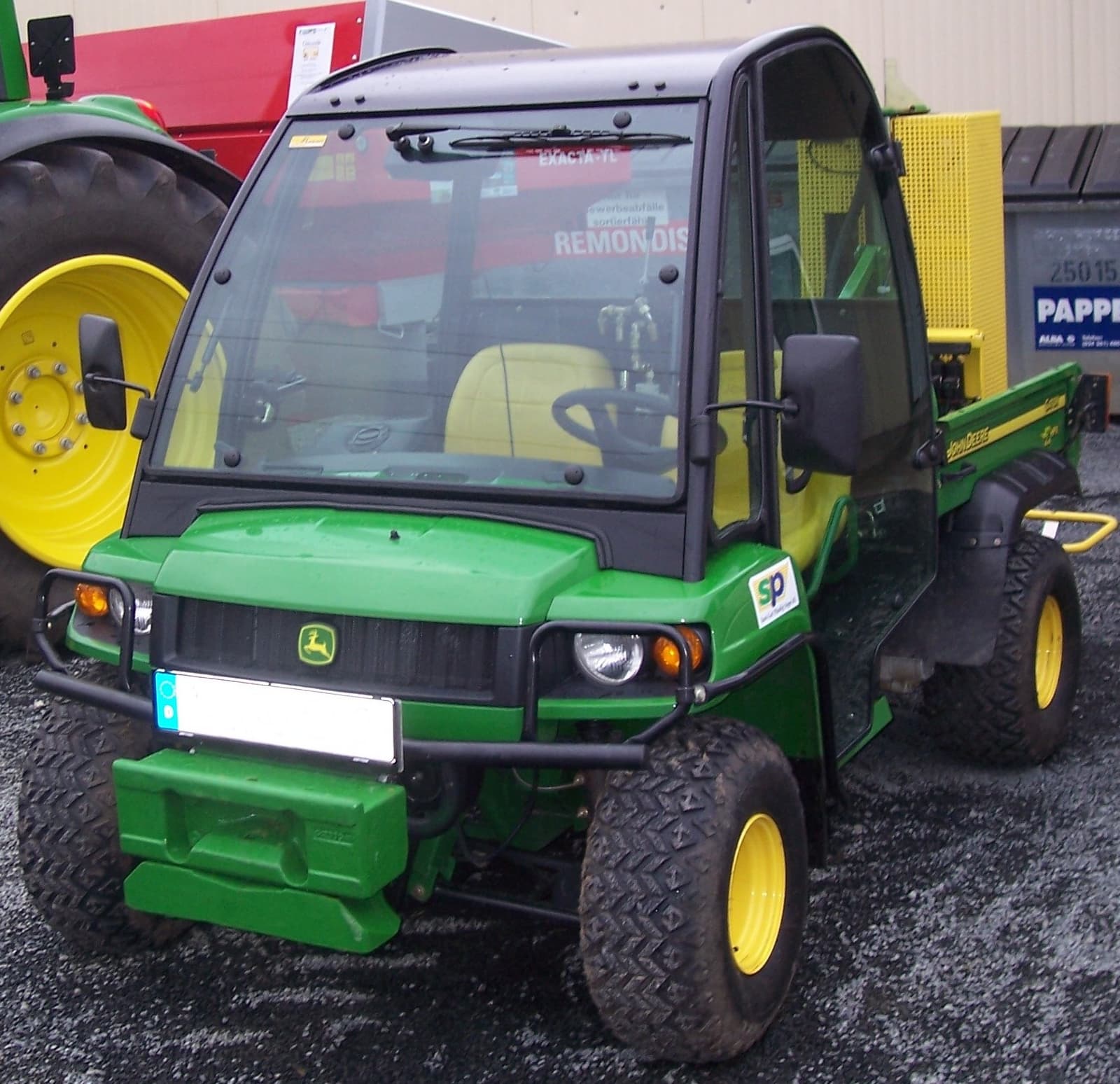 John Deere Gator utility vehicle parked beside farm equipment.