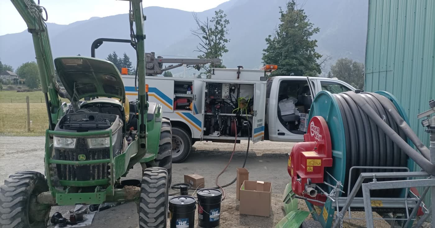 John Deere compact tractor with the hood open for service beside JSD's mobile service truck on a Fraser Valley farm.