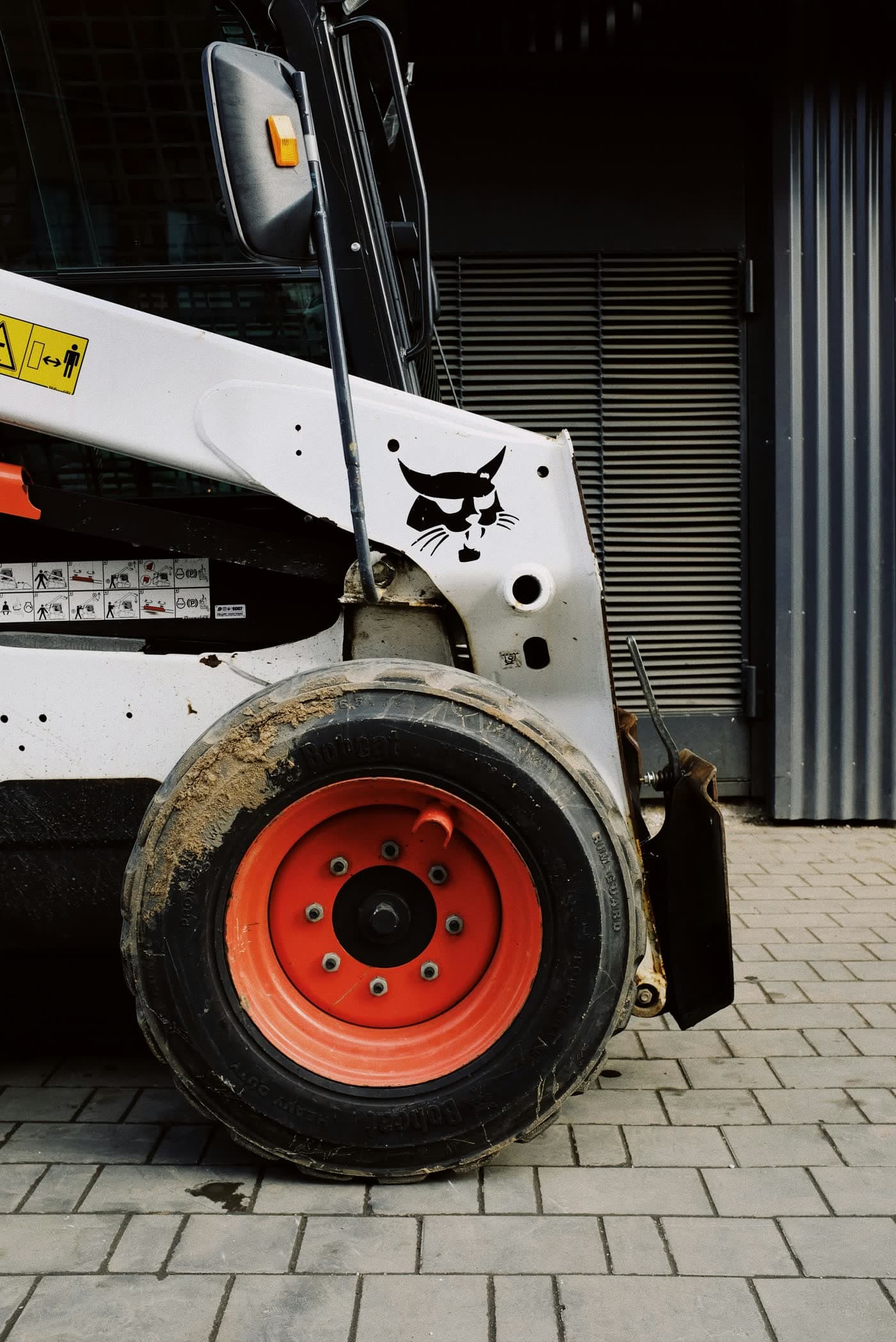 Close-up of a Bobcat skid steer's boom and wheel — typical wear points on a working machine.
