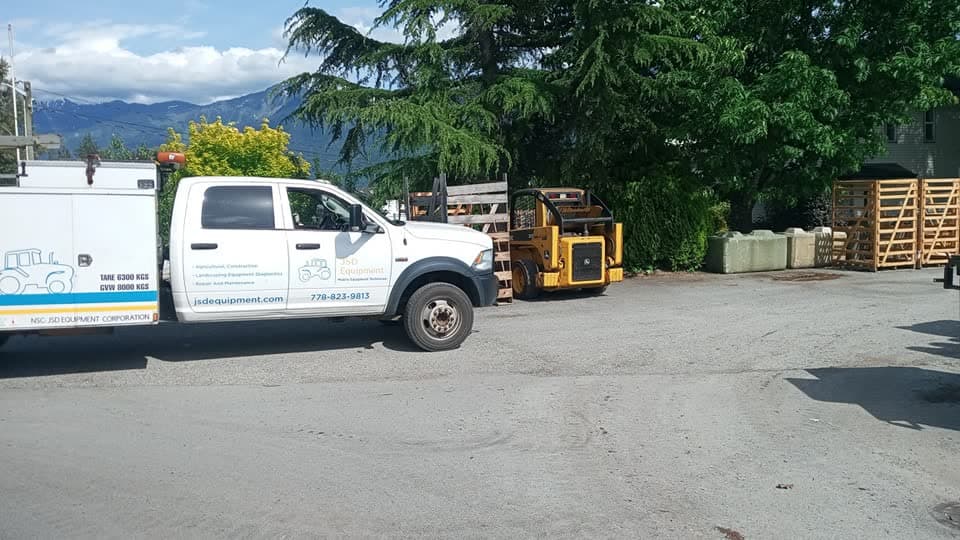 JSD Equipment service truck parked beside a skid steer in the yard.