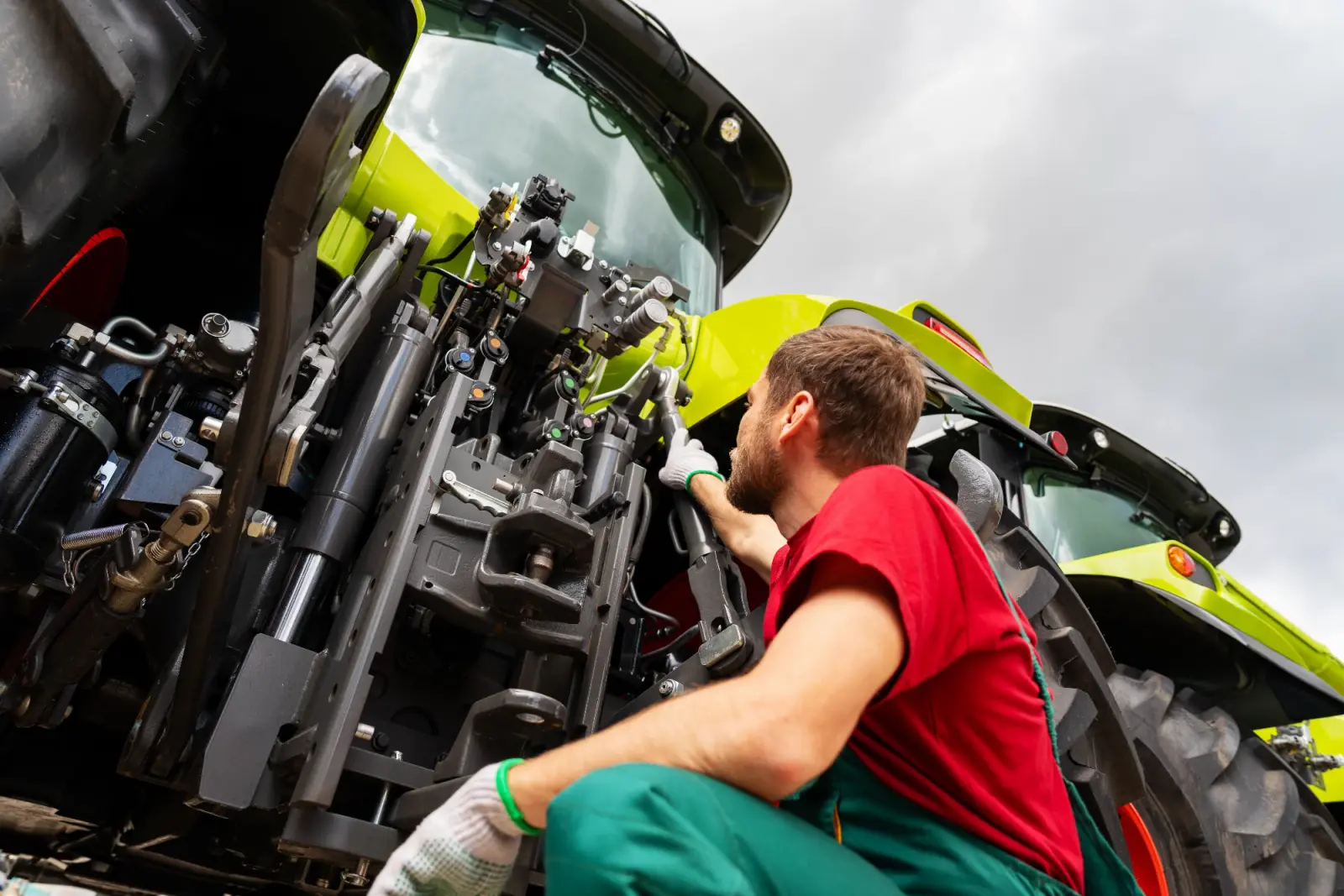 Mechanic inspecting the rear hydraulics of a tractor.
